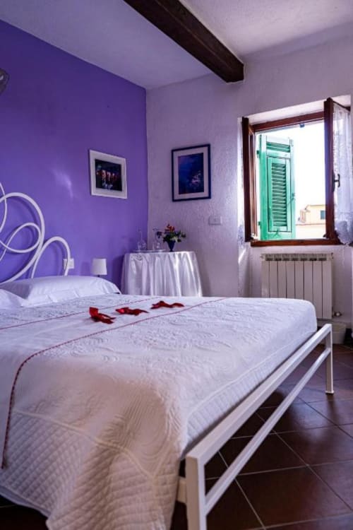 Camera da letto viola con letto bianco presso SoleMagia a Vernazzo, Italia, con vista sulla città e servizi moderni