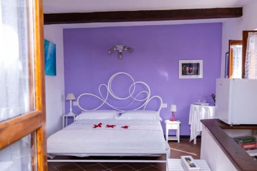 SoleMagia Camera 3 a Vernazzo con parete azzurrata viola, testata bianca decorativa e vista sulla città