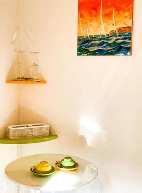 Angolo della camera SoleMagia con dipinto di barca a vela, bicchieri decorativi e arredamento minimalista a Vernazzo