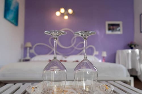 Due calici di vino sul tavolo nella suite SoleMagia con camera da letto in stile viola e vista sulla città di Vernazzo