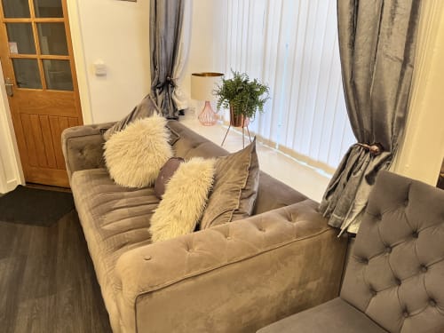 Cozy sitting area in Railway Hotel Haydon Bridge luxury studio with gray velvet sofa, fur pillows, and bright windows