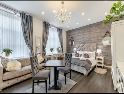 Luxury studio apartment at The Railway Hotel with king bed, seating area, dining table, crystal chandelier, and textured