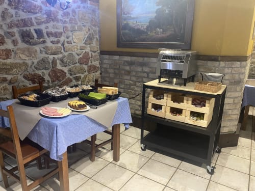 Sala de desayuno de Hotel Rural Los Texos con muros de piedra, buffet servido, tostadora y mesa de comedor en La Riera de