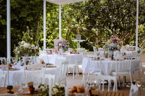 Elegant outdoor wedding reception at Domaine de Bize Mirepoix with white-dressed tables, chairs, and lush green gardens in