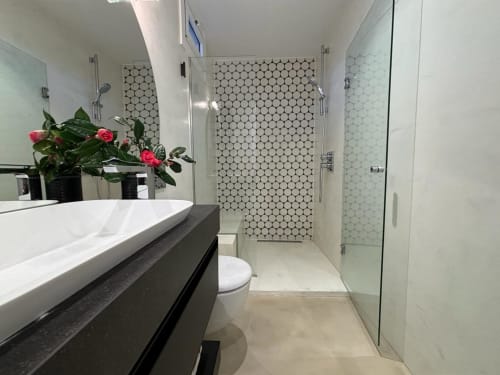 Baño moderno en villa de Panxón con ducha de azulejos hexagonales, lavamanos flotante y griferías elegantes