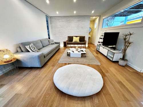 Sala de estar de villa moderna en Panxón, Rías Baixas con sofá gris, puf redondo blanco, suelos de madera y vistas al mar