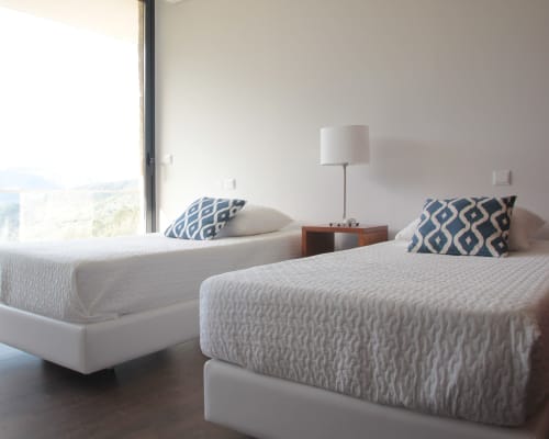 Quarto twin moderno da villa Casa da Luz Gerês com vista para o rio, roupa de cama branca e almofadas com padrão azul