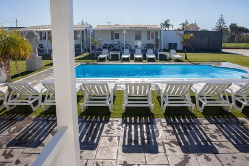 Bungalow Buda Beach pool area in Chipiona with white loungers, crystal blue water, and beachfront bungalows