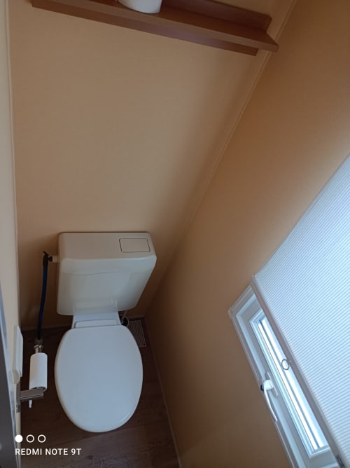 Clean white toilet and sink in bathroom of Bungalow J at Buda Beach hotel, Chipiona with beige walls