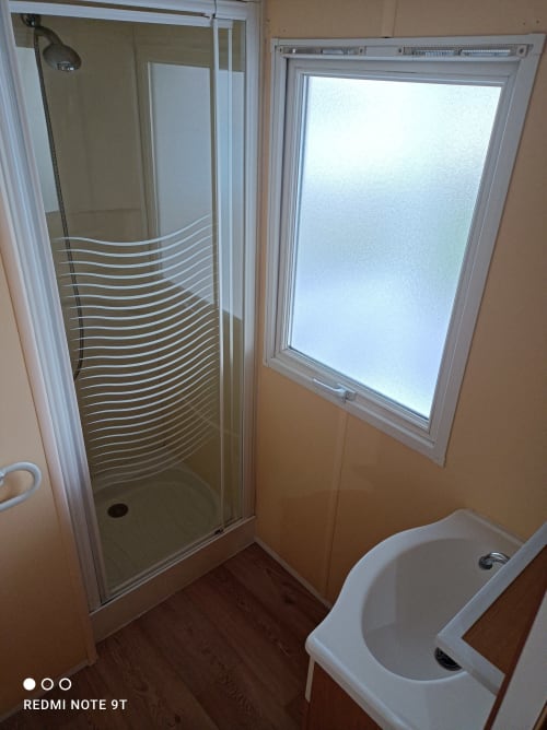 Modern bathroom at Bungalow Buda Beach with glass shower enclosure, white toilet, and window in Chipiona