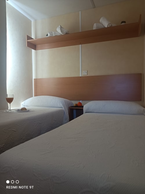 Twin beds in bright bedroom at Bungalow Buda Beach Chipiona with wooden headboard and storage shelves