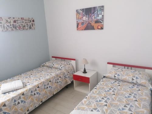 Due letti gemelli con biancheria a motivi geometrici in una luminosa camera da letto dell'appartamento vacanziale La Maison Du Port a Licata, Italia