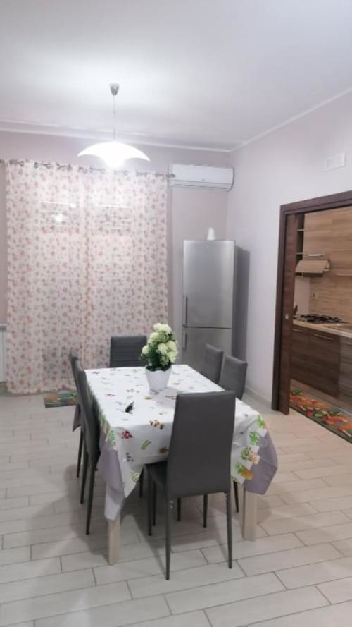 Zona pranzo moderna con tavolo, sedie grigie, lampada a sospensione, frigorifero e accesso cucina in La Maison du Port