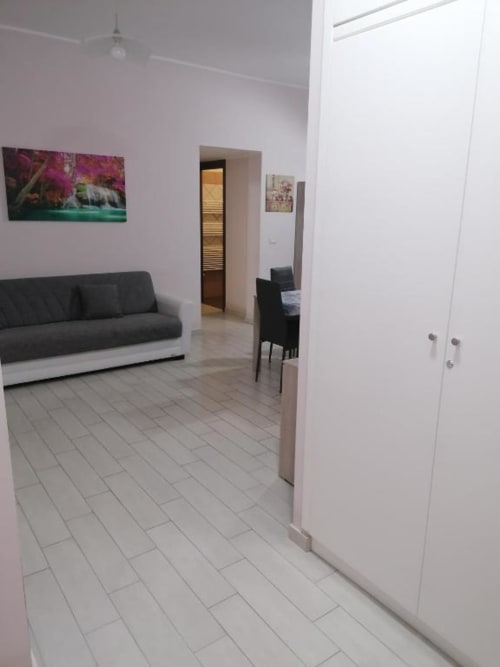 Elegante soggiorno moderno a La Maison Du Port, Licata, con divano grigio, pavimenti in piastrelle bianche e opere d'arte alle pareti