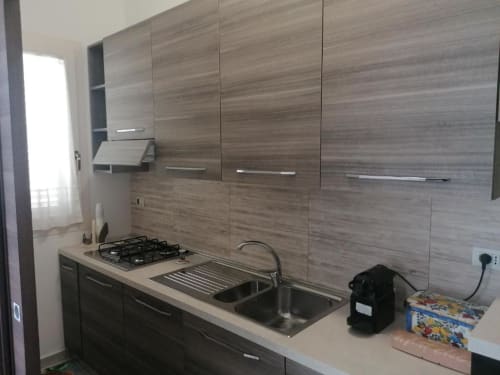 Cucina moderna nella casa vacanze La Maison du Port con piano cottura a gas, lavello e mobili in legno grigio a Licata