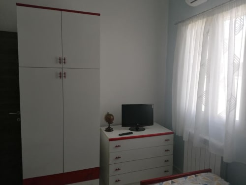 Camera moderna dell'hotel La Maison Du Port a Licata con armadio bianco, cassettiera con TV e molta luce naturale