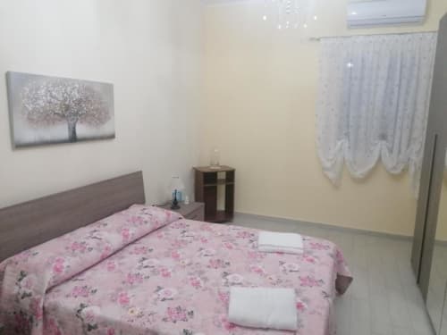 Camera da letto all'hotel La Maison Du Port di Licata con biancheria floreale rosa, testata in legno e quadri alle pareti