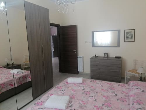 Modern bedroom at La Maison Du Port in Licata with floral bedding, mirror wardrobe, and contemporary furniture