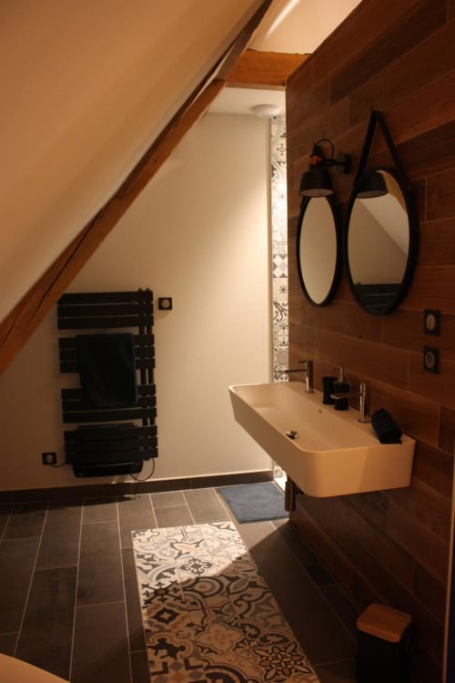 Salle de bain moderne à la Théière & Couverts B&B, Cernay : mur en bois, vasque murale, miroirs ronds et sèche-serviettes