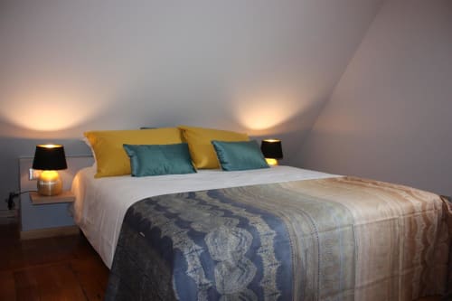Chambre douillette à la Théière & Couverts à Cernay avec coussins jaunes, accents bleu-vert et éclairage plafonnier chaleureux