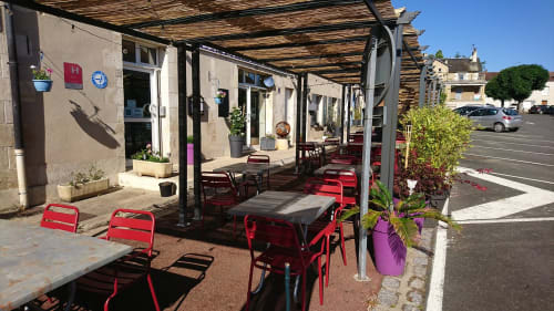 Terrasse extérieure avec chaises rouges et pergola à l'hôtel Les Deux Porches à Verrières, France