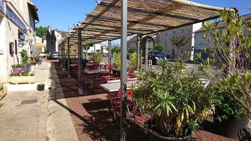 Terrasse extérieure Les Deux Porches avec chaises rouges, pergola et plantes à Verrières