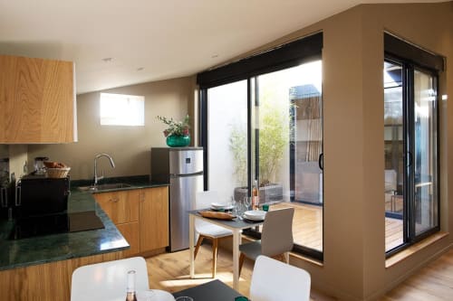 Modern kitchen and dining area at AJOUCADOU BnB Lourmarin with wood cabinetry, stainless appliances, and terrace access
