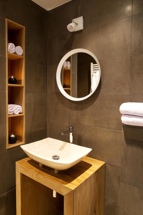 Modern bathroom at AJOUCADOU Lourmarin with wooden vanity, white stone sink, and round mirror