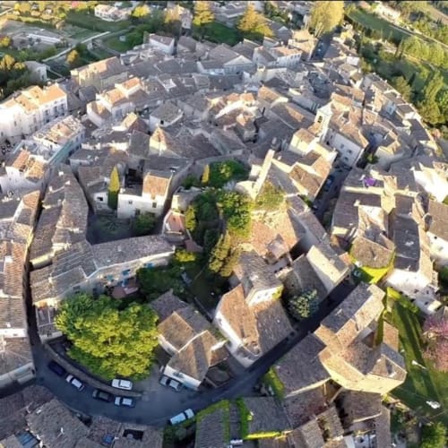 Aerial view of Lourmarin village showing traditional Provençal stone houses with terracotta roofs clustered together,