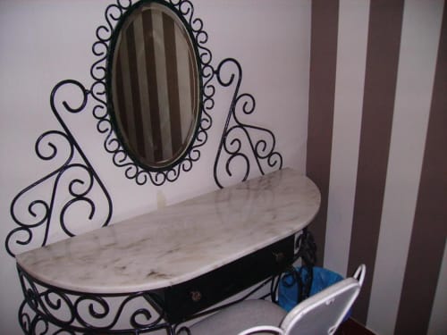 Tocador de metal negro ornamentado con espejo ovalado y encimera de mármol en el hostal Ocean View Lagos