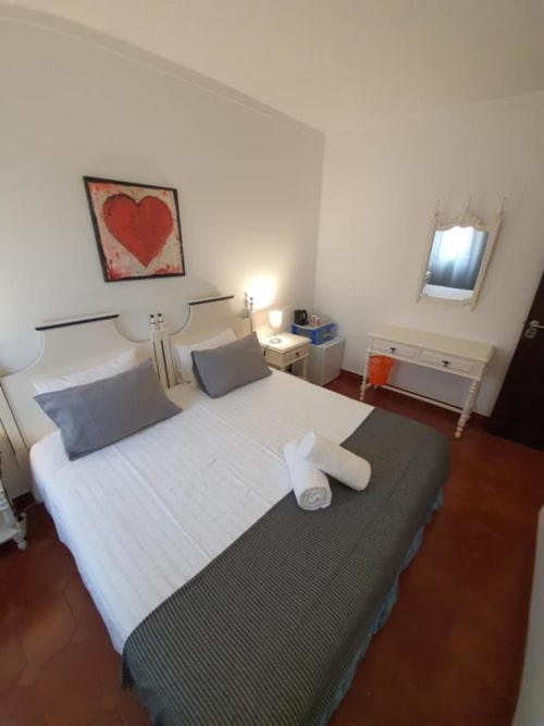 Economy double room at Ocean View Lagos hostel with white bedding, blue pillows, heart artwork, bedside lamp, and shared