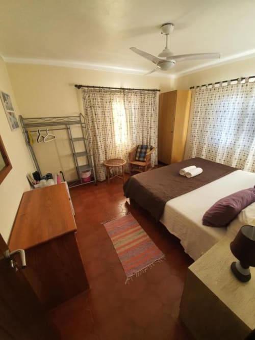 Habitación doble en el albergue Ocean View Lagos con camas, ventilador, muebles de madera y vistas al jardín