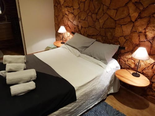 Cozy double bedroom at Ocean View Lagos hostel with stone accent wall, white bedding, gray pillows, bedside lamps, wooden