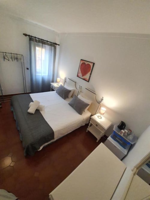 Economy Double Room at Ocean View Lagos hostel in Lagos with bed, nightstands, heart artwork, window with curtains, and warm