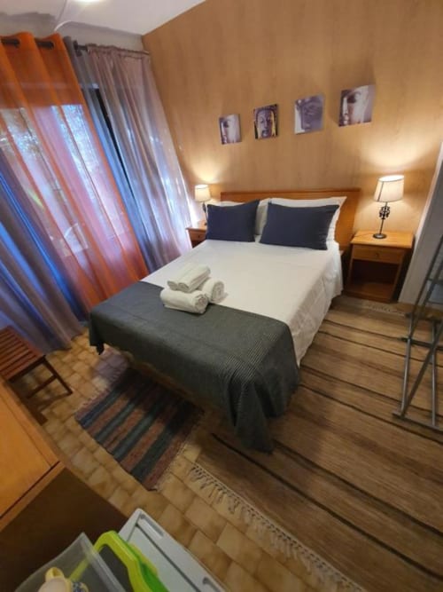 Dormitorio doble en el albergue Ocean View Lagos con ropa de cama blanca, almohadas negras, muebles de madera e iluminación cálida