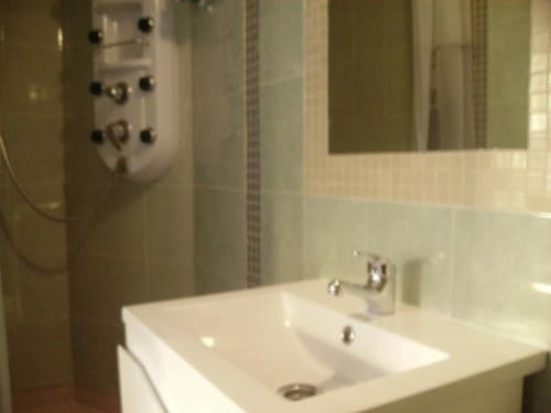 Baño moderno con lavamanos blanco, espejo y cabina de ducha en el hostal Ocean View Lagos