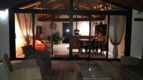 Villa Gites De La Grande Borderie à Saint Gervais avec portes vitrées modernes ouvrant sur les espaces repas et séjour, en soirée