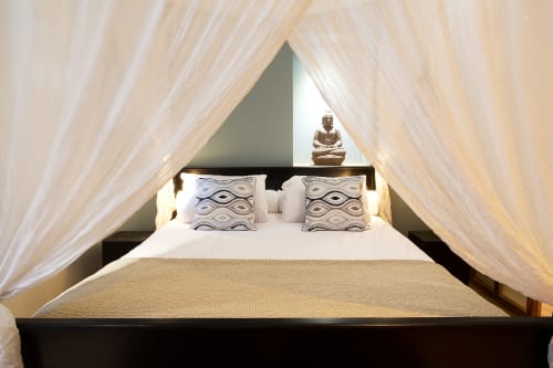 Luxurious canopy bed with sheer drapes in VIP Lodge at AJOUCADOU Lourmarin, featuring patterned pillows and city view