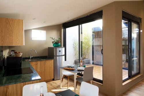 Cuisine et salle à manger modernes à AJOUCADOU à Lourmarin avec portes vitrées coulissantes ouvertes sur la terrasse