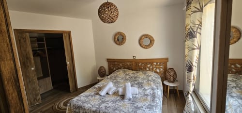 Modern villa bedroom at Villas-Majos with wooden carved headboard, woven pendant light, and sea view in Porto-Vecchio,