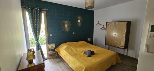 Bedroom with dark teal accent wall, yellow bedding, modern decor, and sea view at Villas-Majos in Porto-Vecchio