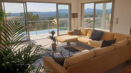 Luxury villa living area with panoramic mountain views, tan sectional sofa, and terrace access in Sainte-Lucie de