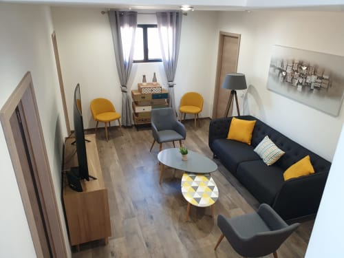 Salon moderne de la villa Villas-Majos avec canapé noir, chaises jaunes et décoration contemporaine à Porto-Vecchio