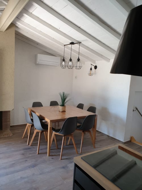 Salle à manger moderne avec table en bois, chaises noires et luminaires géométriques à la villa Villas-Majos