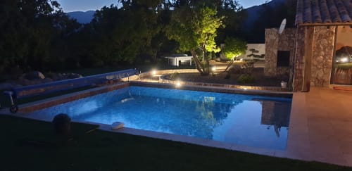 Piscine illuminée aux Villas-Majos à Porto-Vecchio, Corse, entourée d'un paysage méditerranéen de nuit