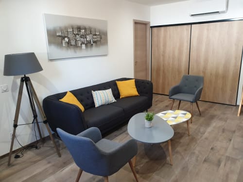 Coin salon moderne à Villas-Majos avec canapé noir, fauteuils, table ronde et décoration contemporaine