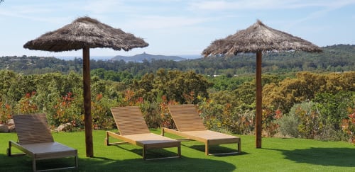 Chaises longues de luxe sous des parasols en paille avec vue sur les vignobles et montagnes aux Villas-Majos, Corse