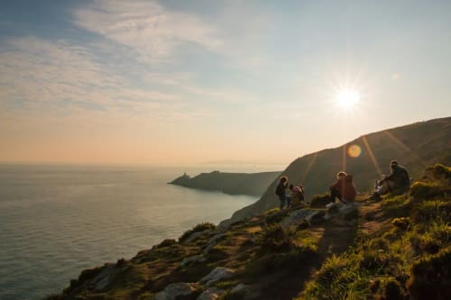 Tourists enjoying coastal cliffs at sunset near Dublin, Ireland with scenic ocean views