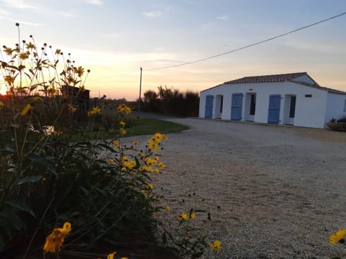 Villa blanche aux Gîtes De La Borderie à Saint-Gervais avec fleurs jaunes au coucher du soleil