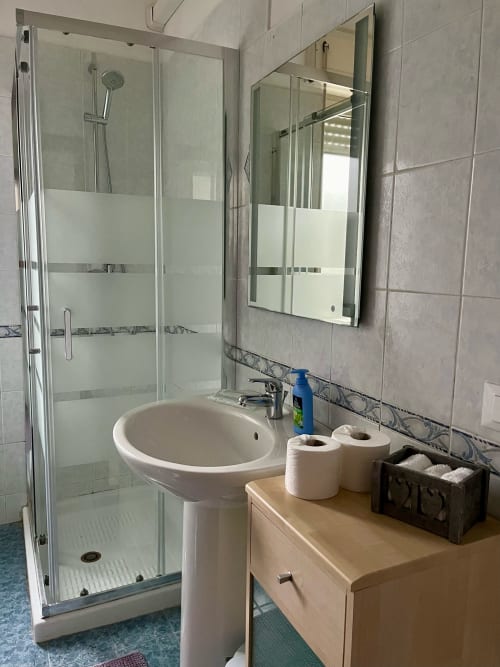Moderno bagno dell'Apartment Tirreno con lavabo su colonna, cabina doccia e specchio a Tirrenia